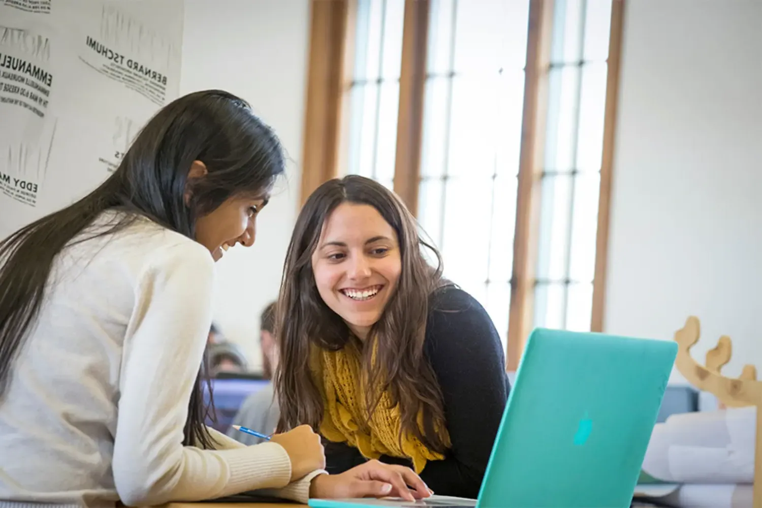 Two students, working together at a laptop,